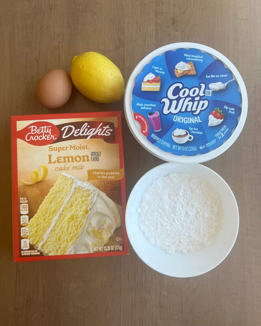 box of lemon cake mix, egg, lemon, cool whip and powdered sugar.