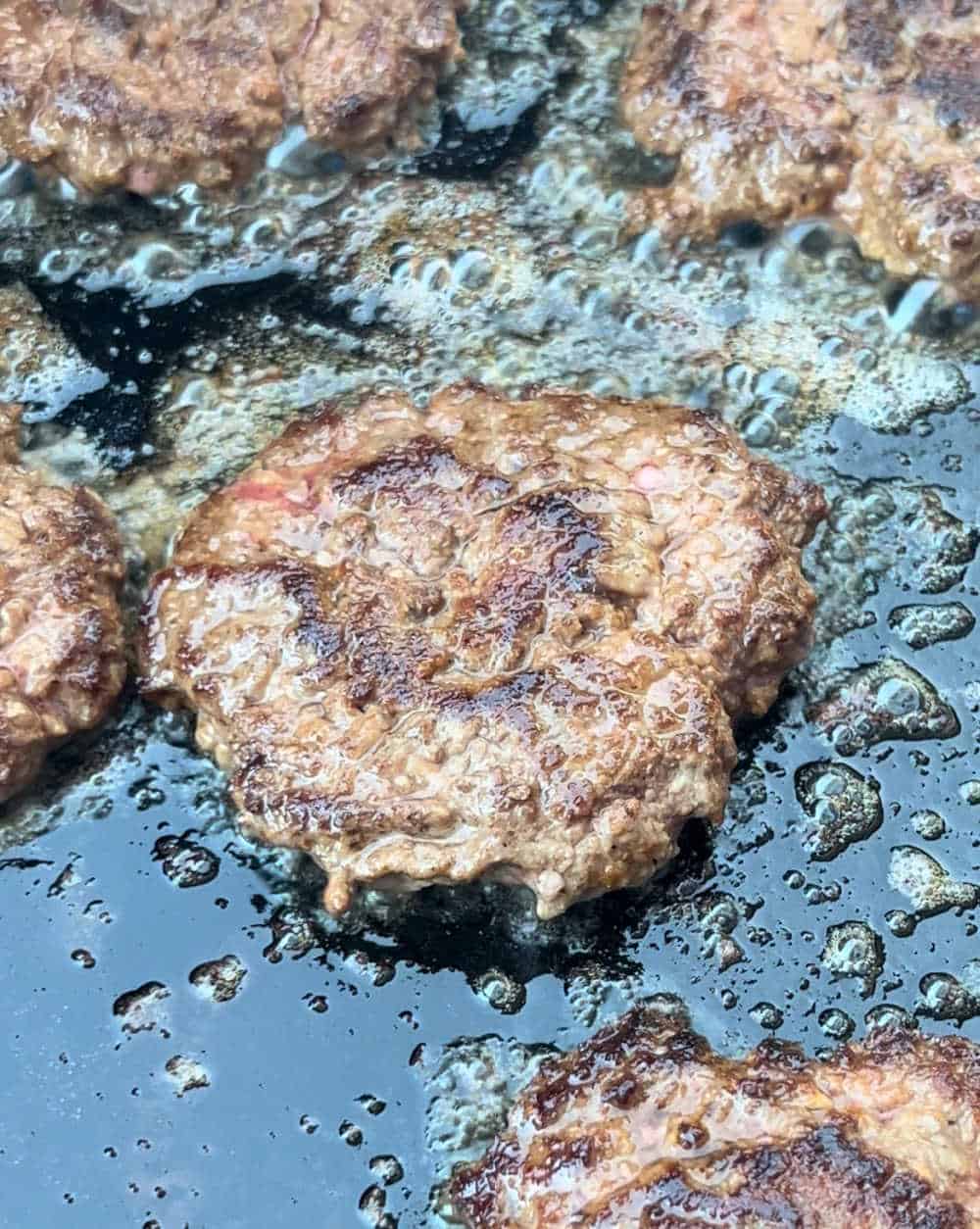 burgers cooking on blackstone griddle.