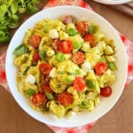 tortellini pasta salad with pesto sauce in white serving bowl.