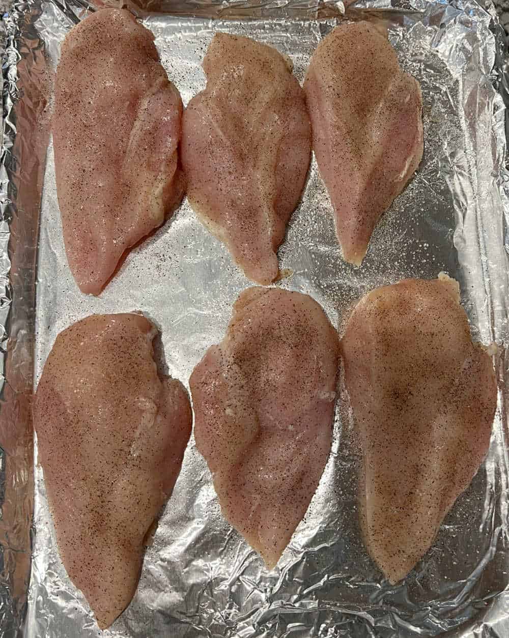 boneless skinless chicken breast on baking sheet.