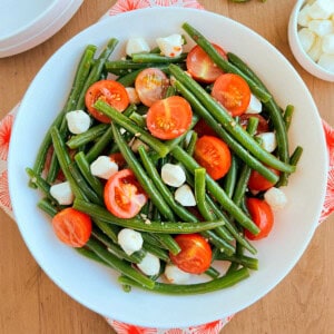 green bean and tomato salad with mozzarella pearls in a bowl.