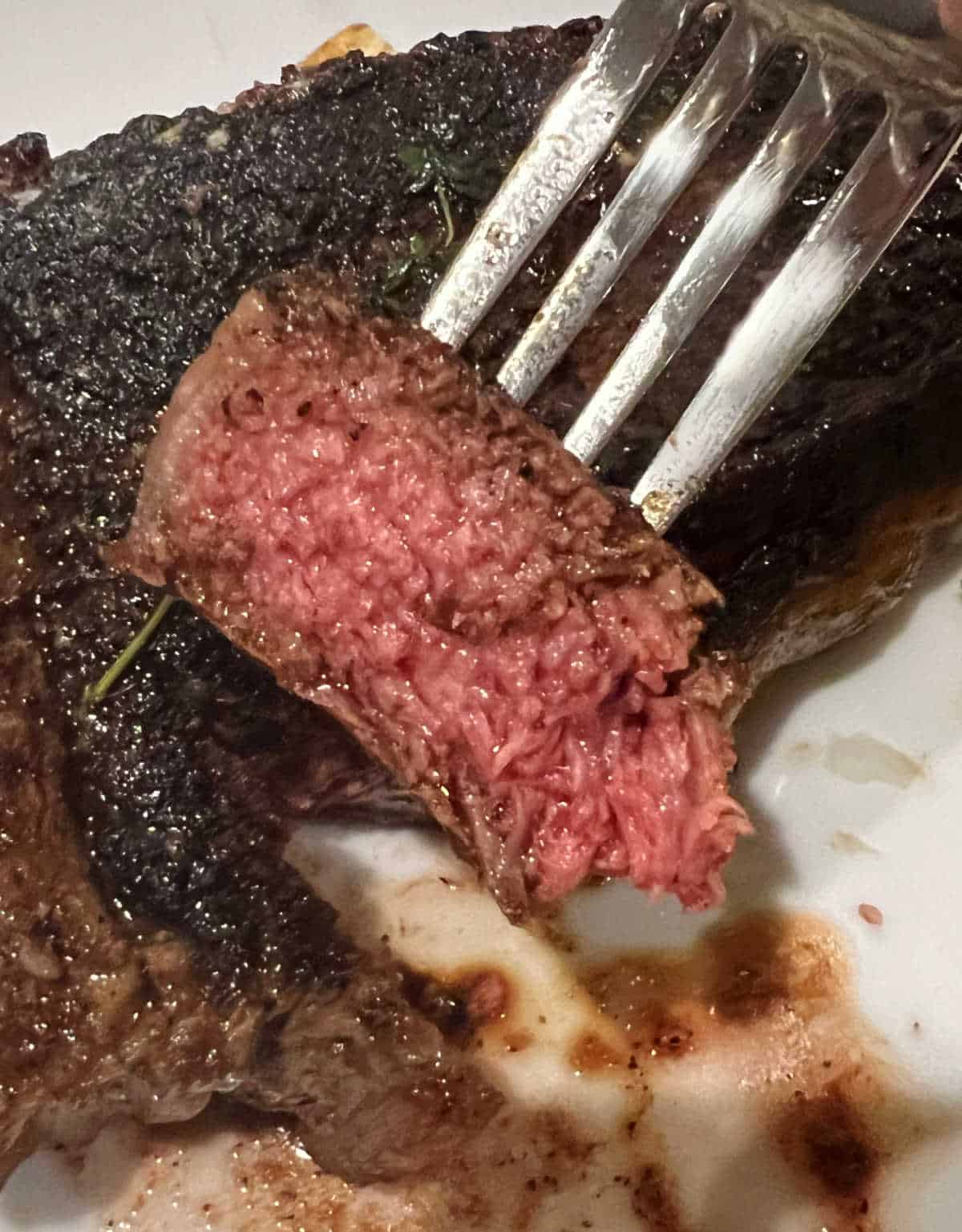 slice of medium rare steak on a fork.