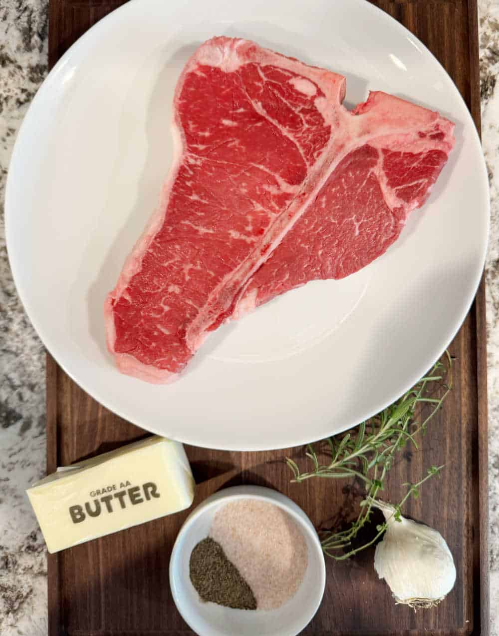 raw porterhouse steak, butter, salt, pepper, garlic, rosemary and thyme.