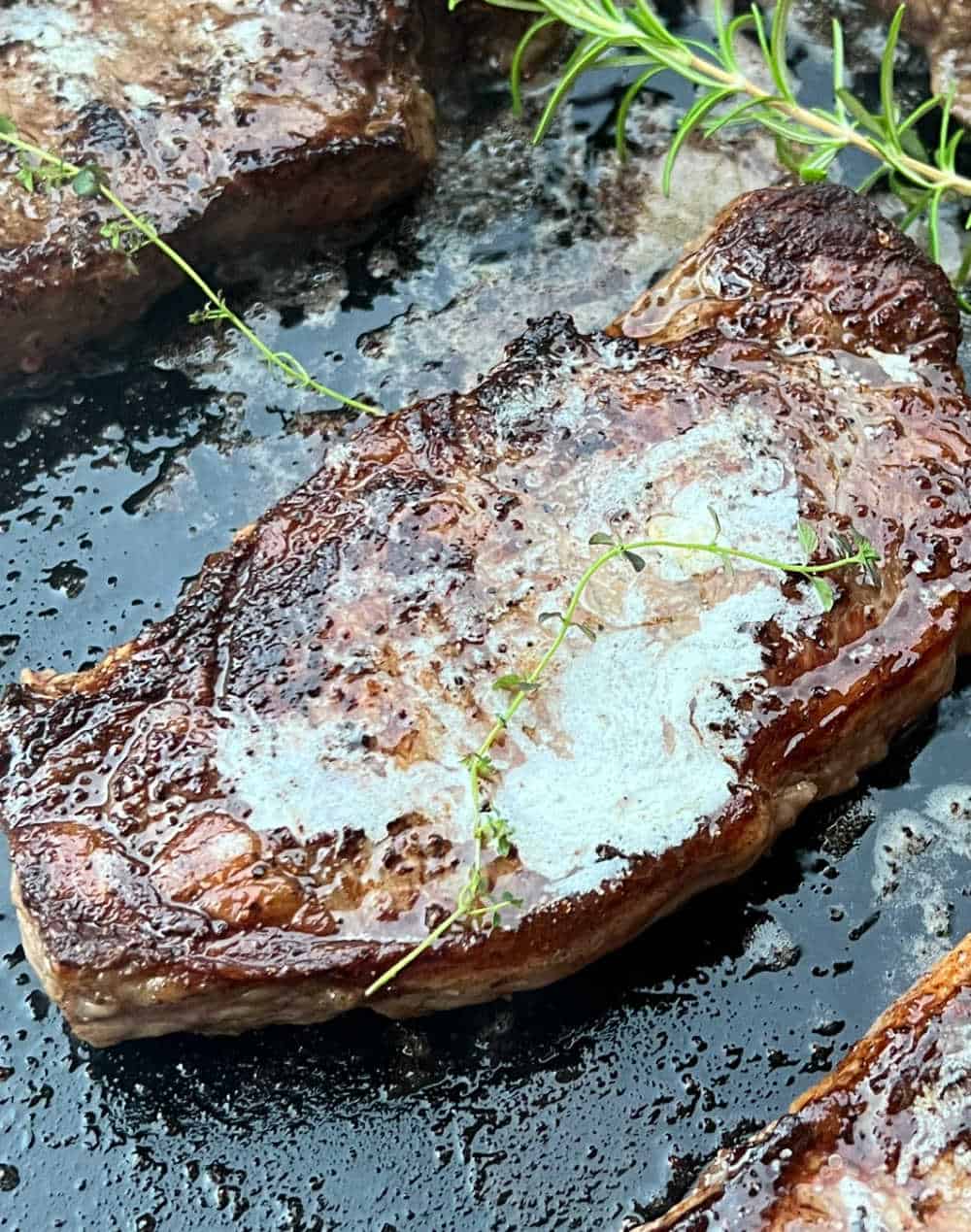 New York steak with rosemary and thyme on blackstone.