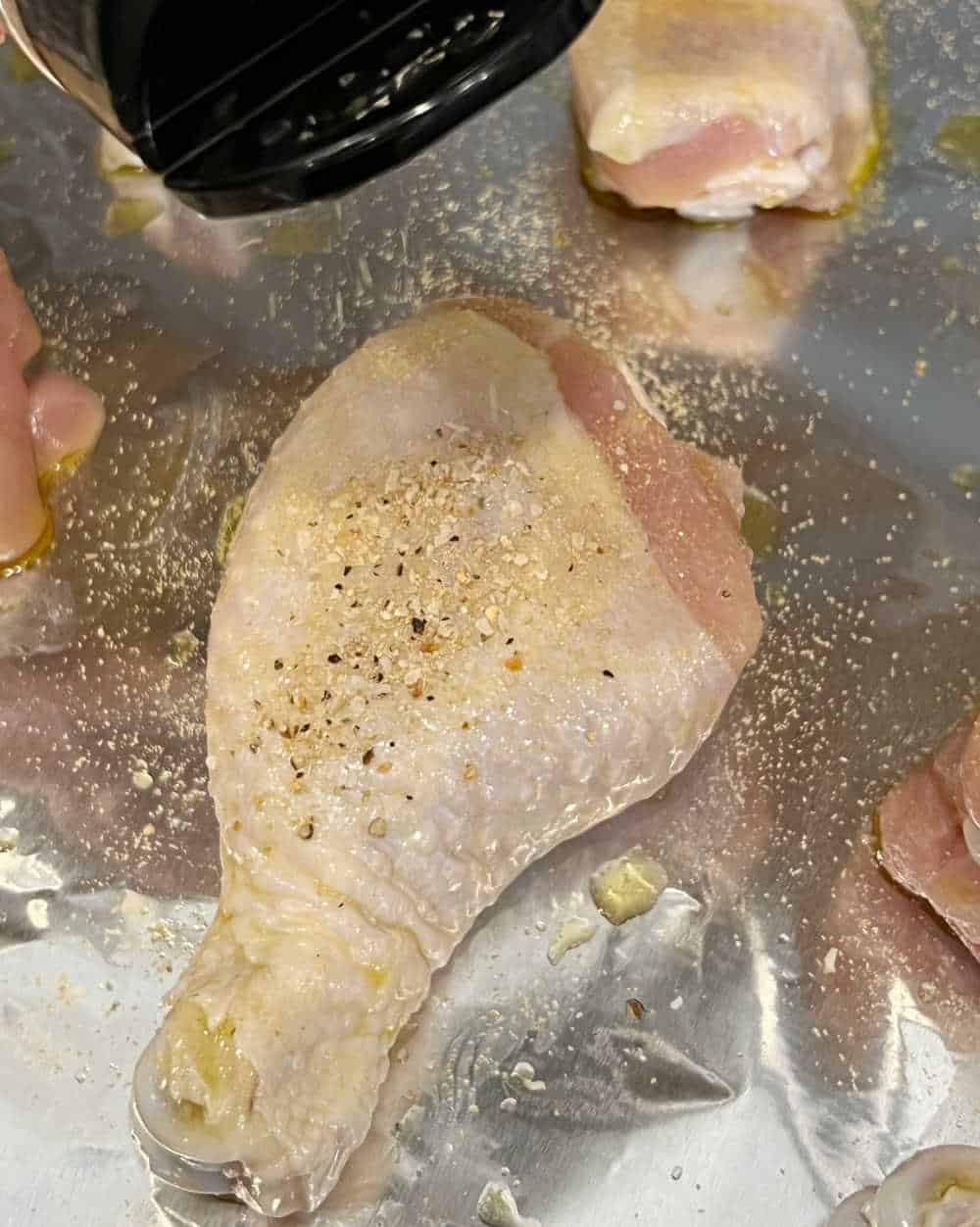 season chicken drumsticks on baking sheet.