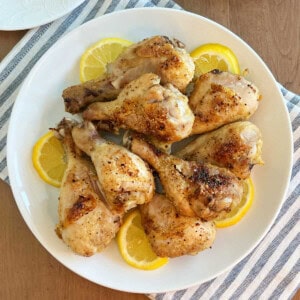 plate of baked chicken legs with lemon slices.