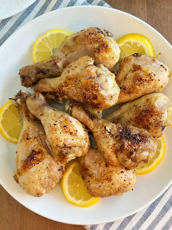 plate of baked chicken legs with lemon slices.