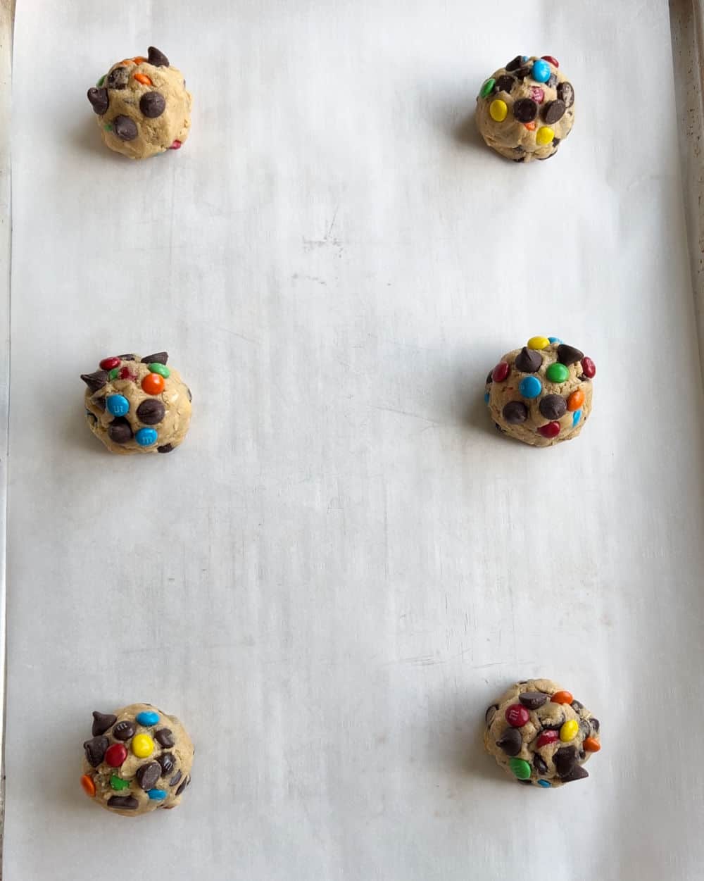 monster cookie dough balls on baking sheet.