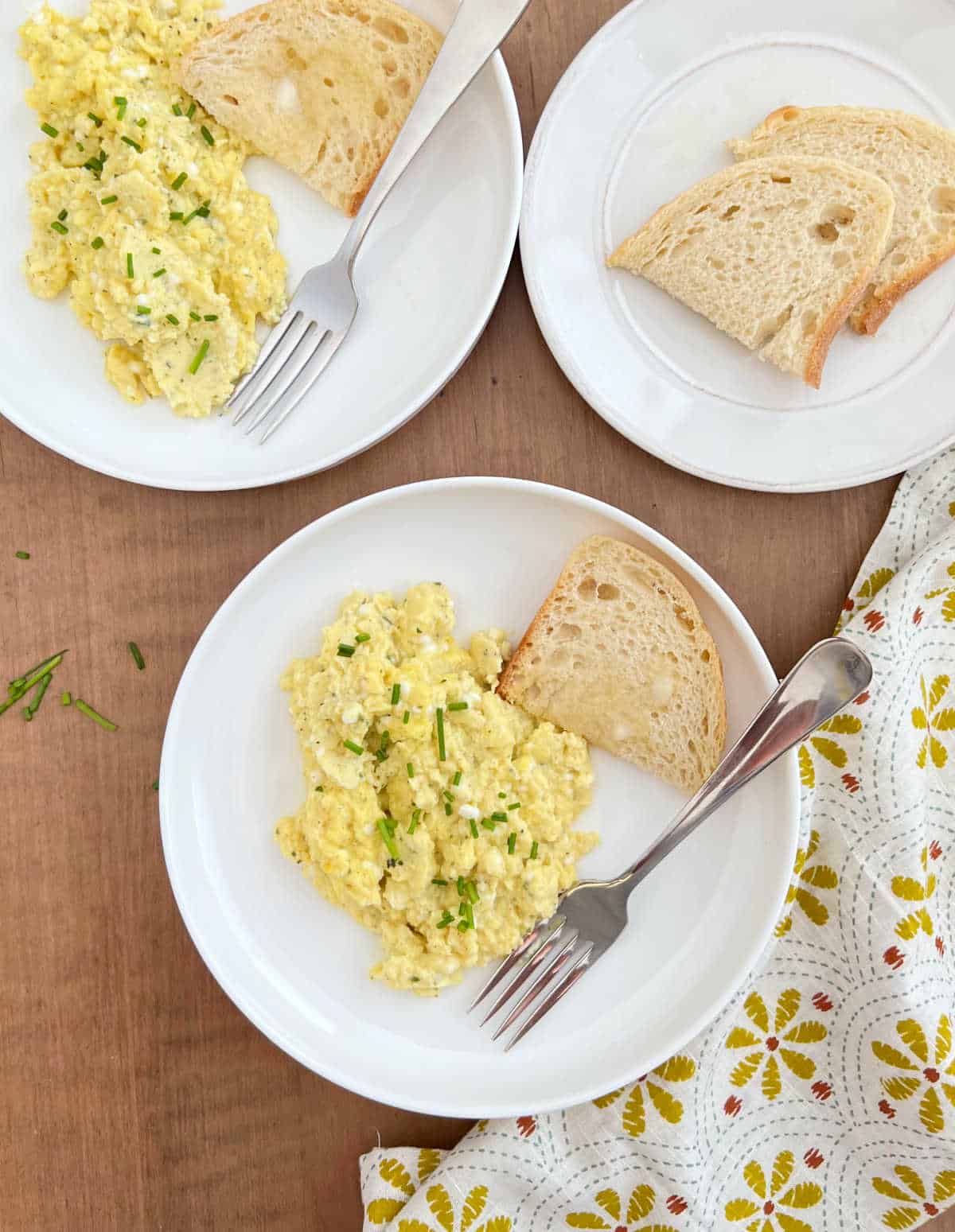 plates of cottage cheese scrambled eggs with chives and toast.