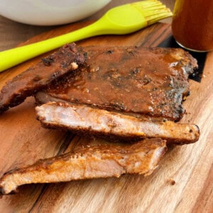 electric smoker smoked ribs with bbq sauce on cutting board.