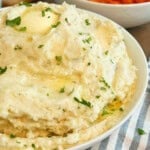 bowl of cream cheese mashed potatoes with butter and parsley.