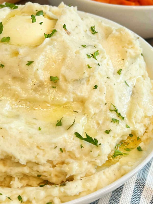 bowl of cream cheese mashed potatoes with butter and parsley.