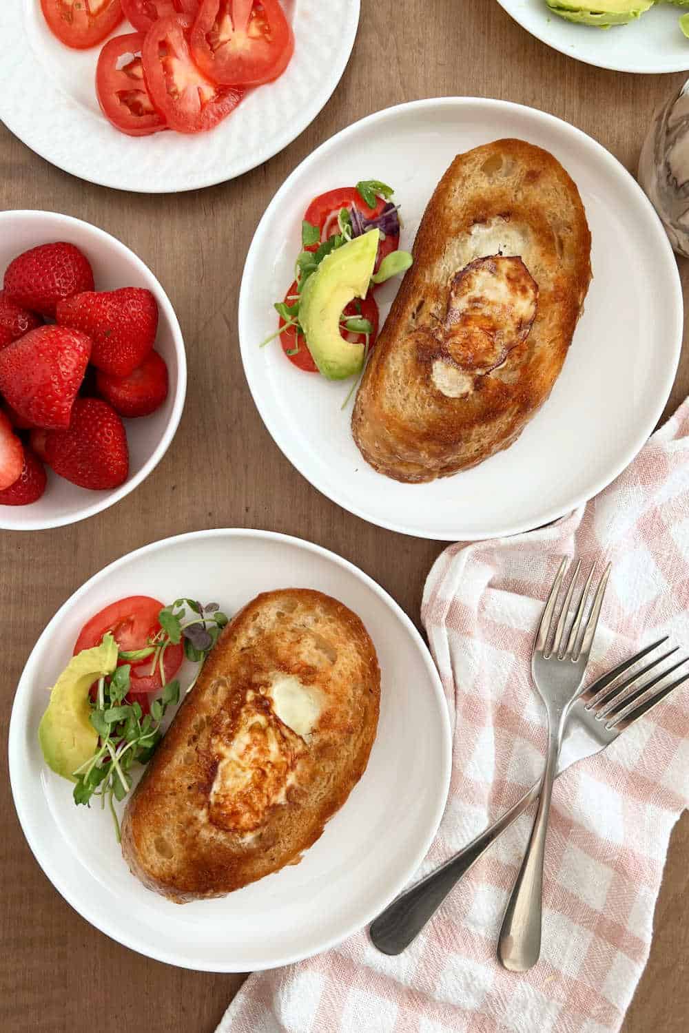 plates of egg in a hole on breakfast table.