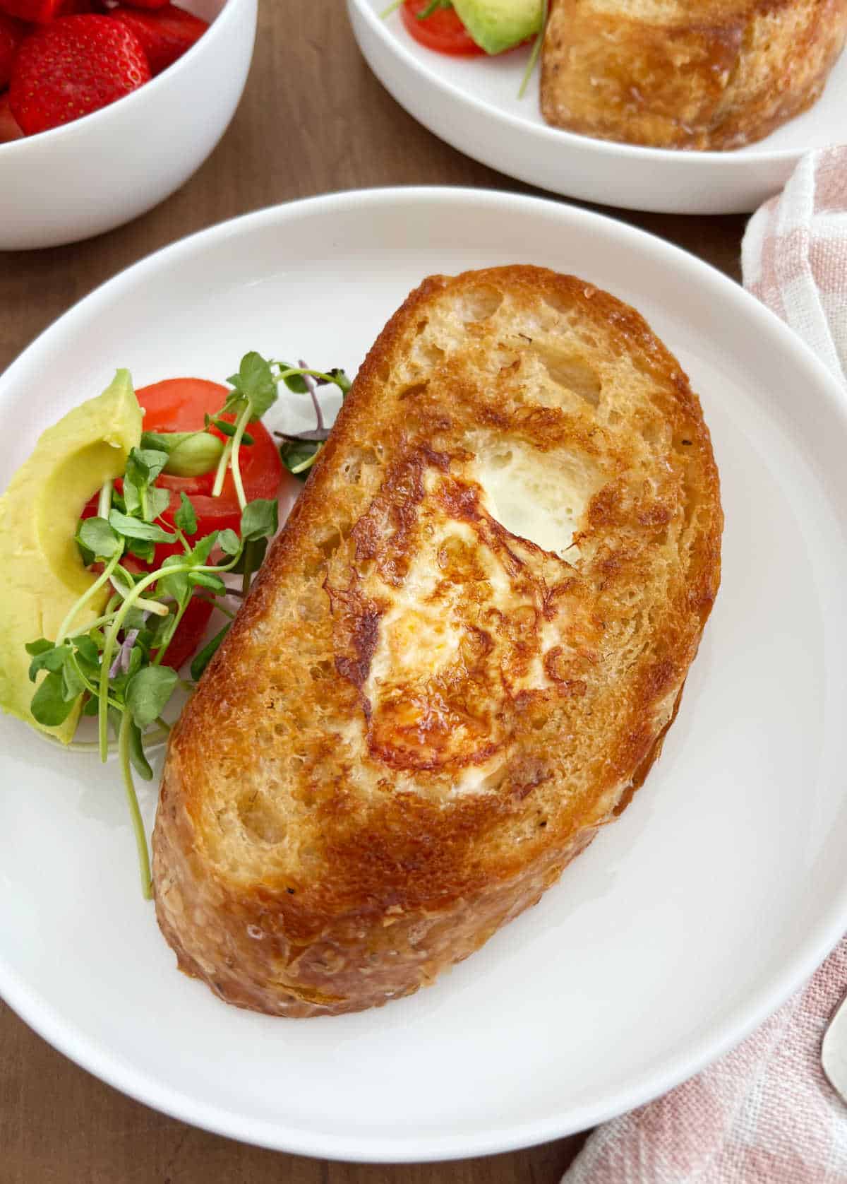 egg in a hole in sourdough toast on white plate.