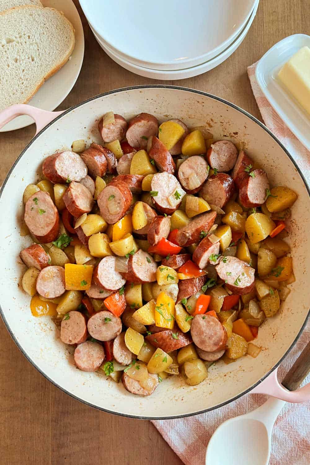 fried kielbasa and potatoes with peppers and onions in skillet.