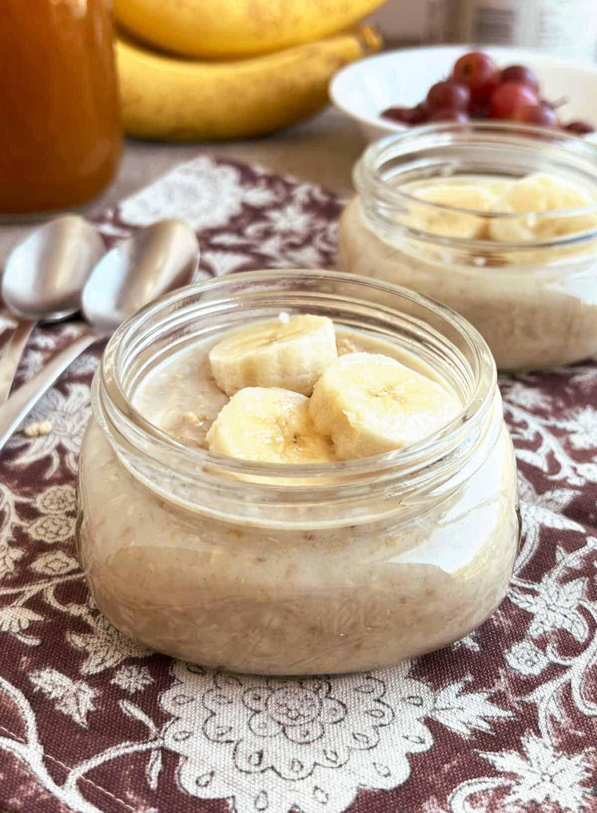 mason jars with overnight oats topped with banana slices on the table.