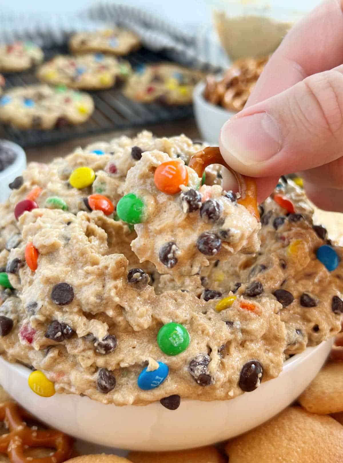 monster cookie dough dip on pretzel in hand.