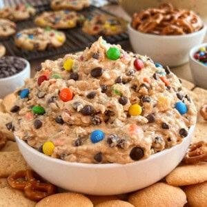 bowl of monster cookie dough dip with cookies and pretzels on the table.