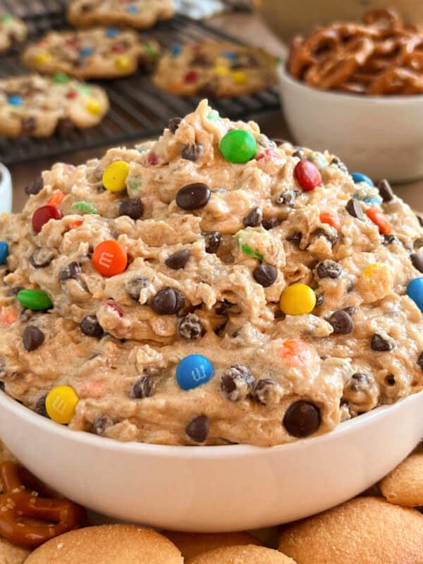 bowl of monster cookie dough dip with cookies and pretzels on the table.