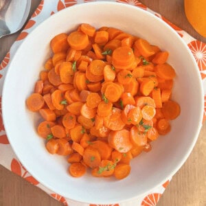 bowl of orange glazed carrots with parsley.