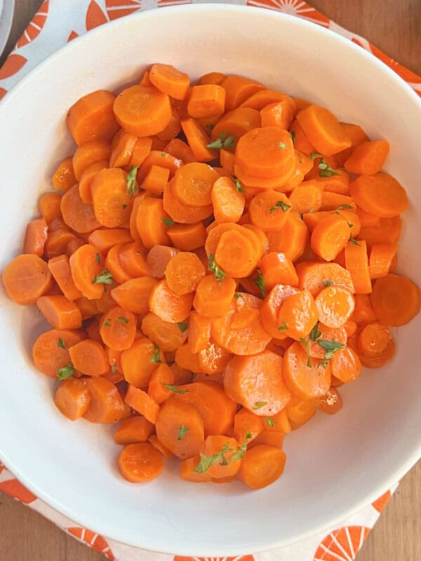 bowl of orange glazed carrots with parsley.