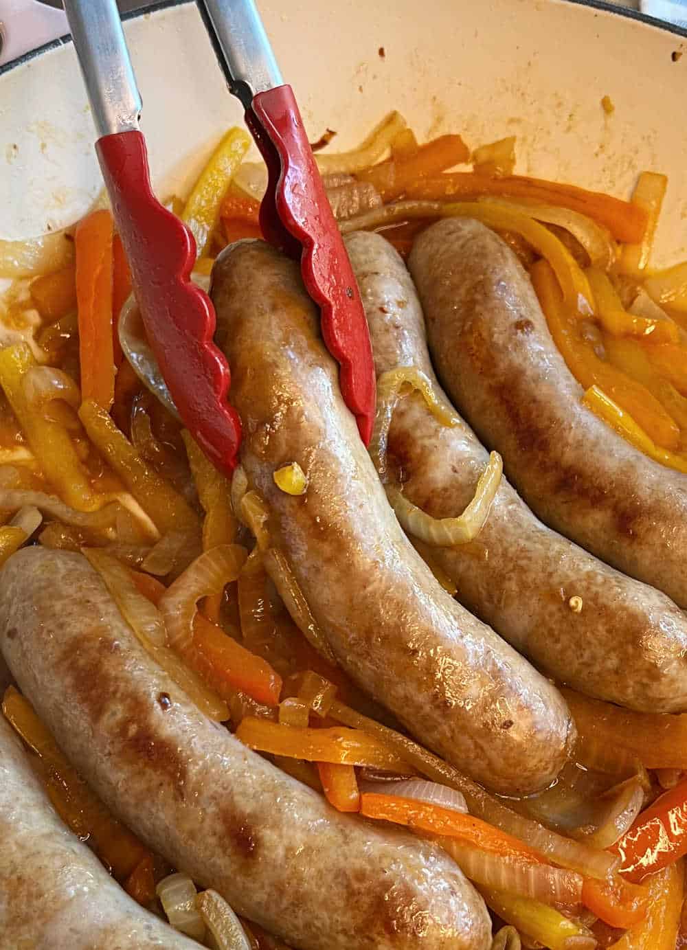 flip sausages with kitchen tongs in skillet.