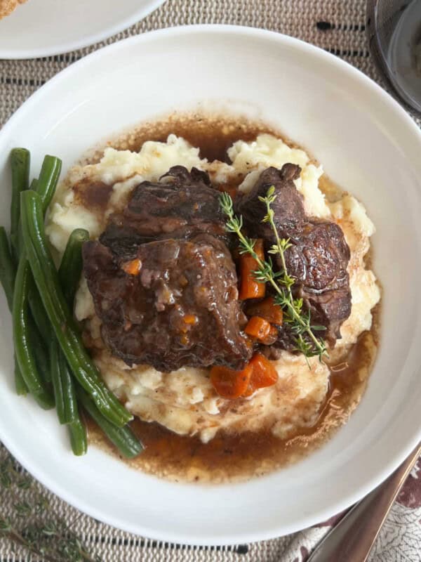 braised short ribs over mashed potatoes on plate.