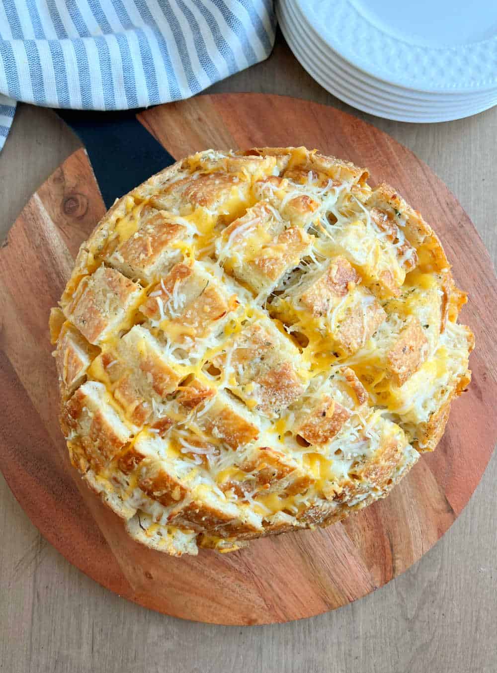 baked garlic bread loaf stuffed with melted cheese on cutting board.