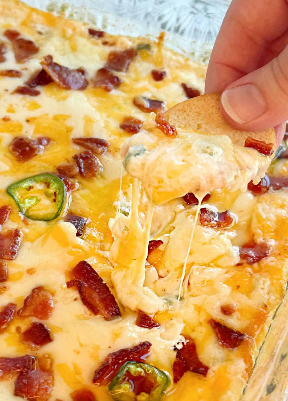 jalapeno popper dip with bacon and melty cheese on a chip.