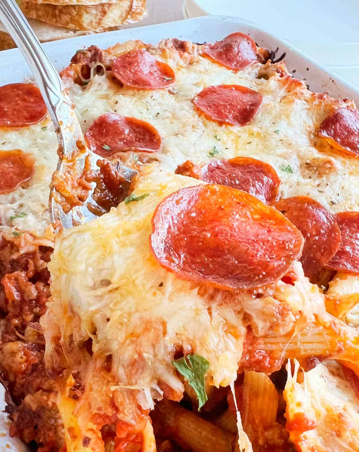 pepperoni pizza pasta bake with melty cheese on a serving spoon.