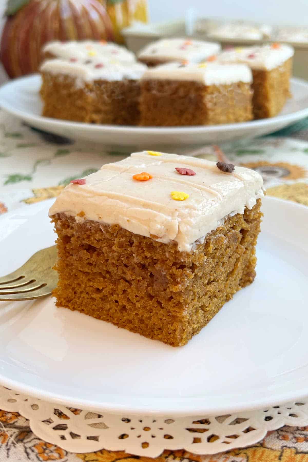 pumpkin bars with cream cheese frosting on fall table.