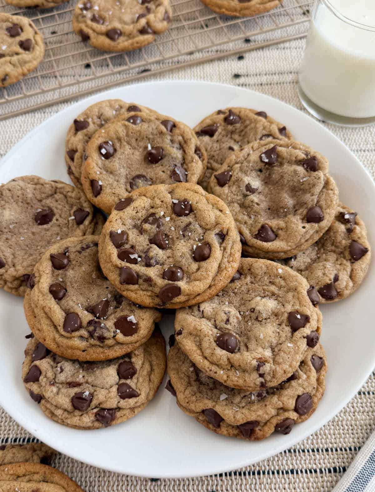 chocolate chip cookies with flaky salt on a plate with milk.