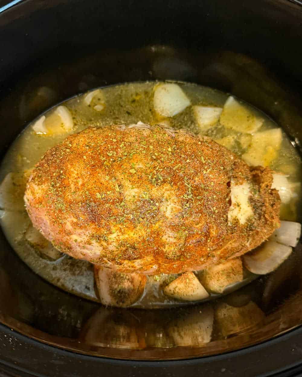 seasoned turkey breast roast in crock pot with broth and onion.