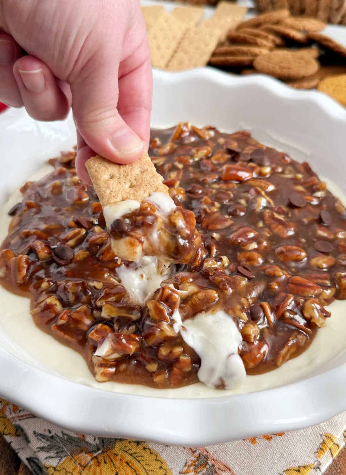 hand dipping graham cracker in pecan pie dip.