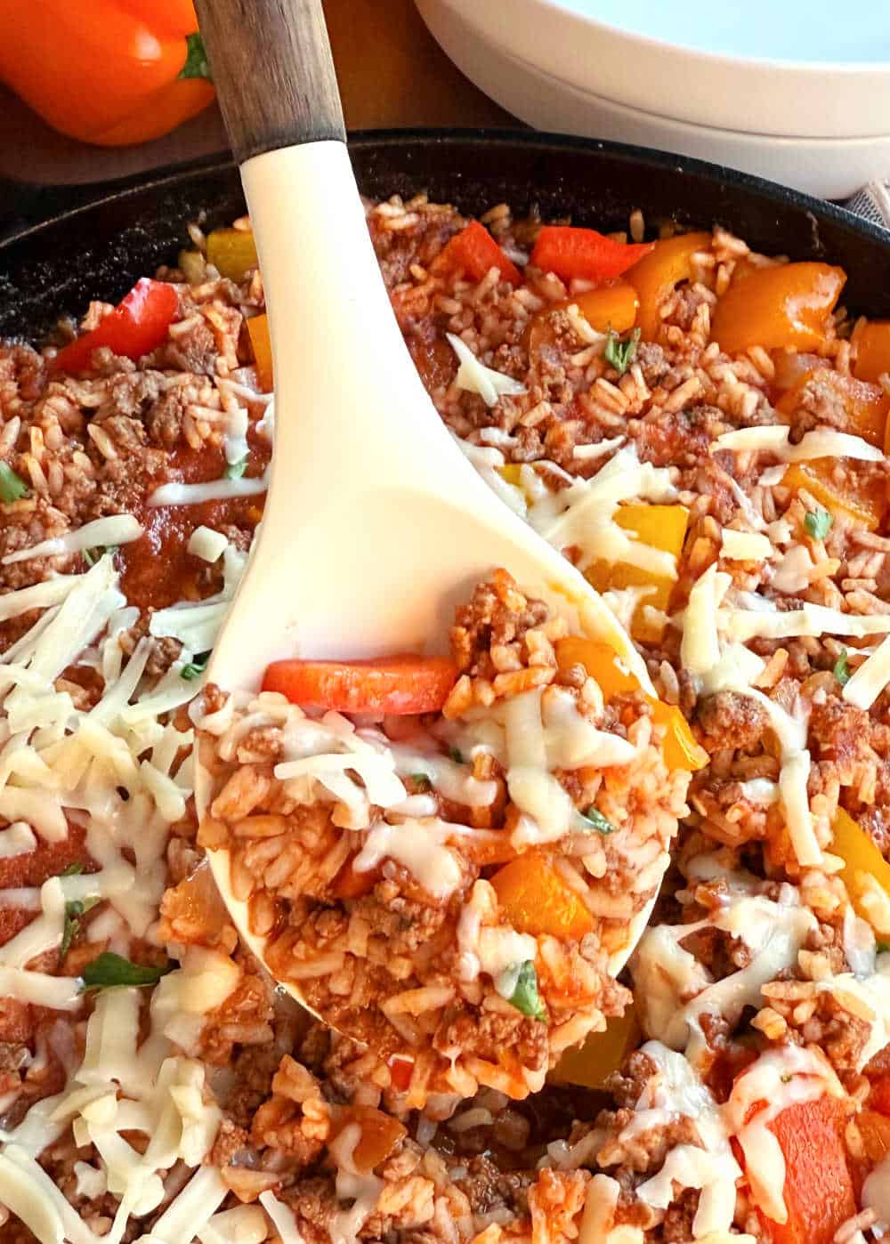 unstuffed peppers with melted cheese on serving spoon in skillet.