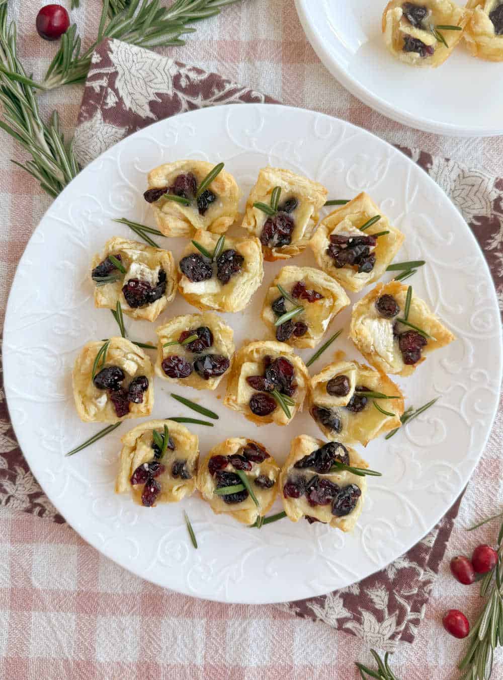 plate of baked brie bites with cranberries and rosemary.