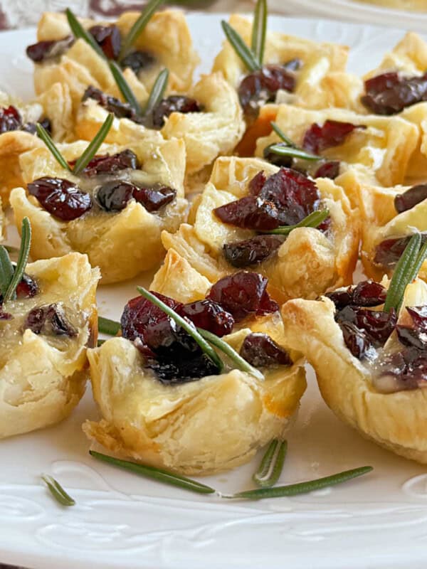 cranberry brie bites with rosemary on plate.