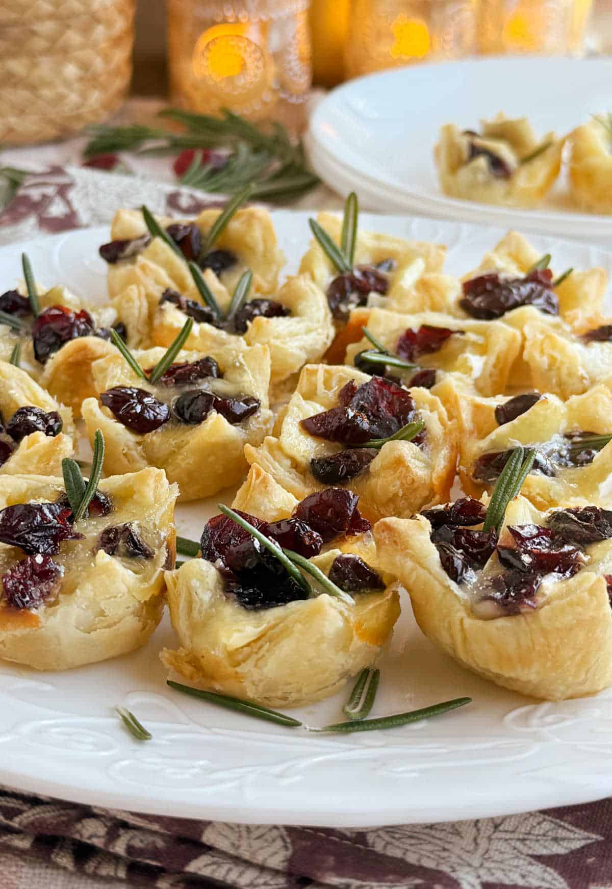 cranberry brie bites in puff pastry with dried cranberries and rosemary.