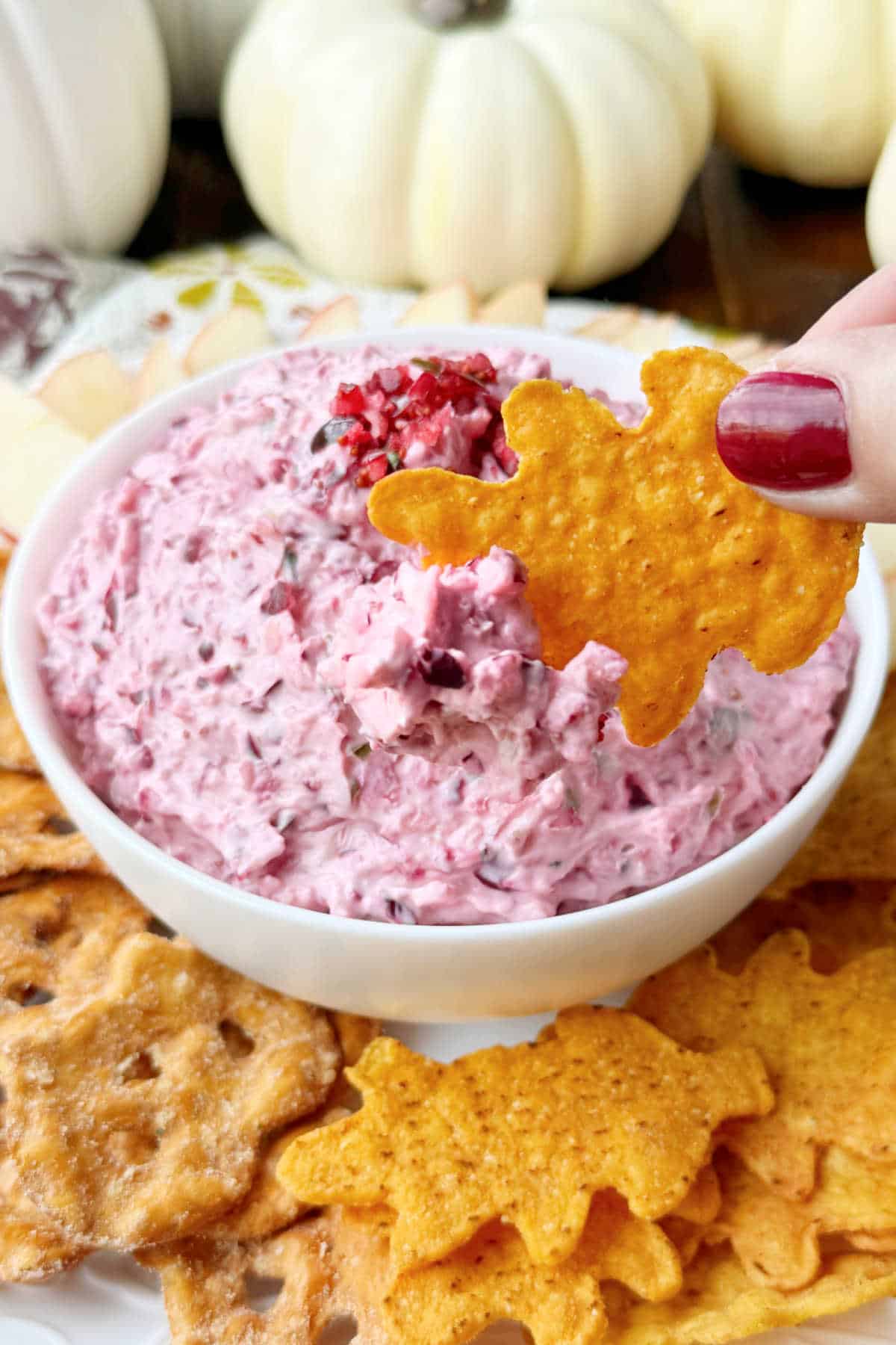 cranberry jalapeno cream cheese dip on leaf shaped tortilla chip.