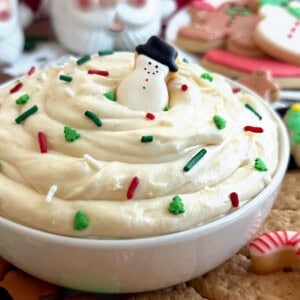 Christmas sugar cookie dip with snowman cookie in white bowl.