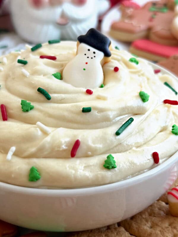 Christmas sugar cookie dip with snowman cookie in white bowl.