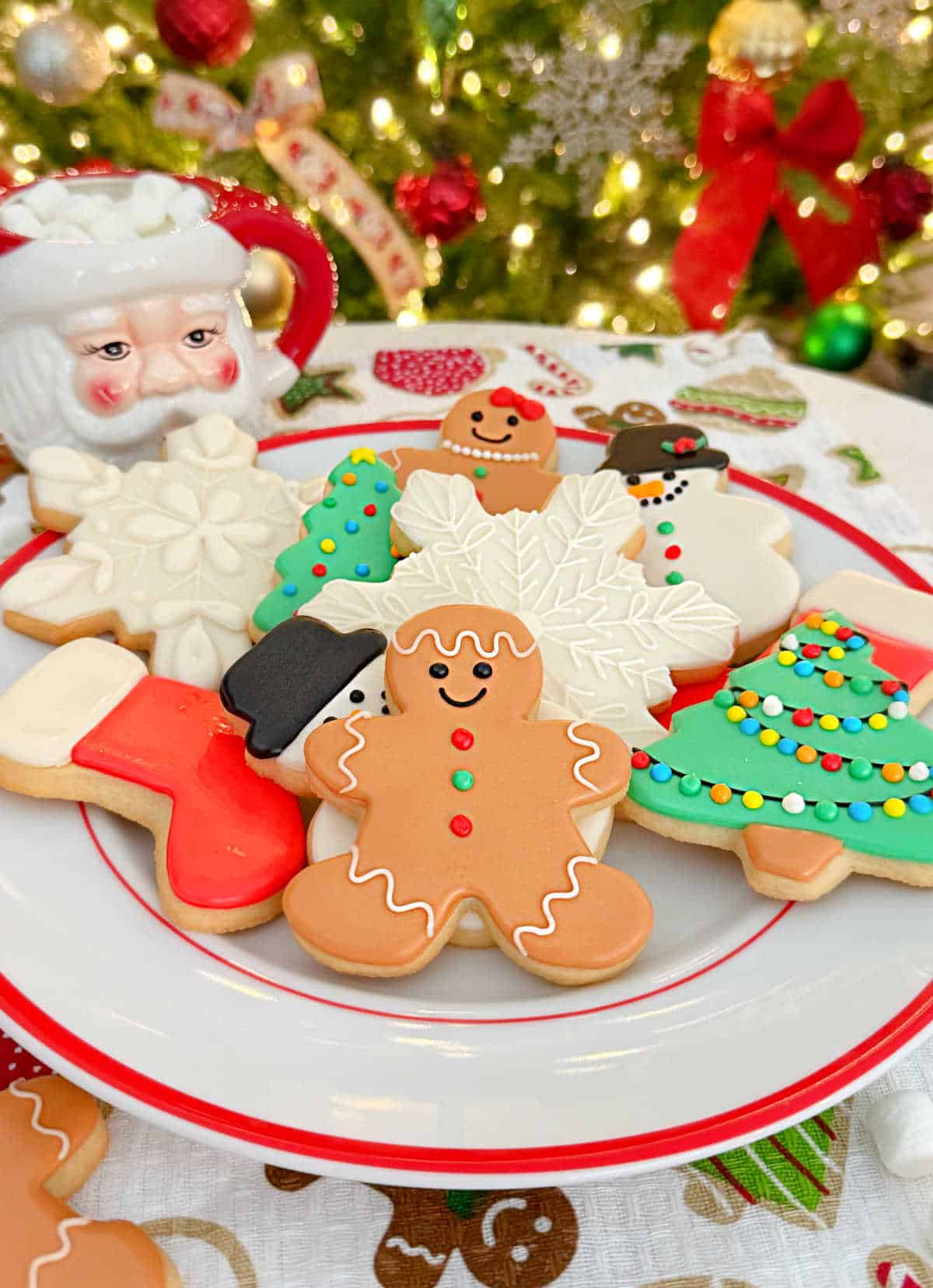 plate of adorable christmas sugar cookies by Christmas tree.