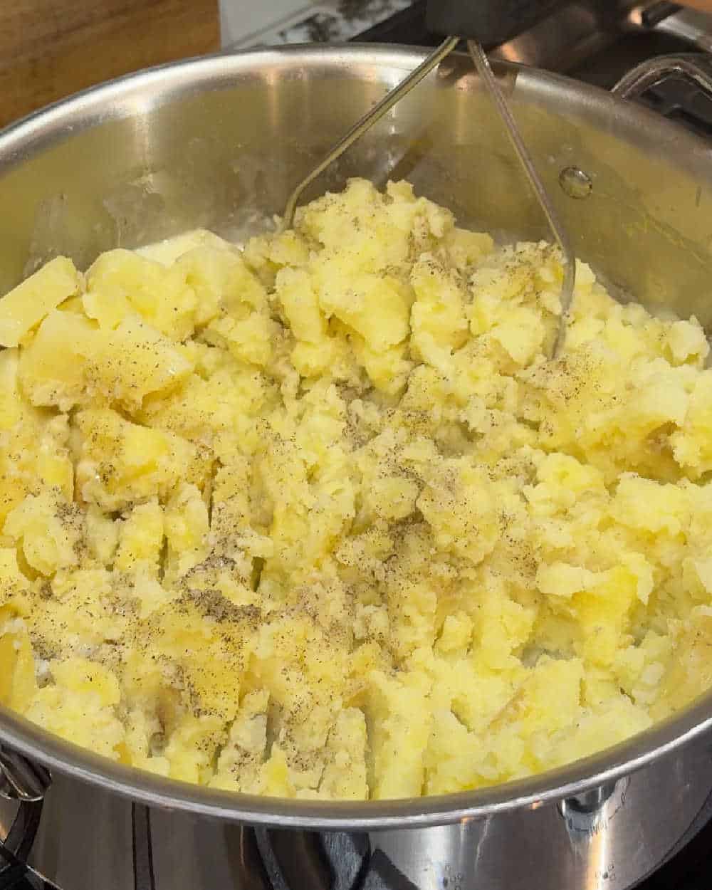 mashing with potato masher in pot.