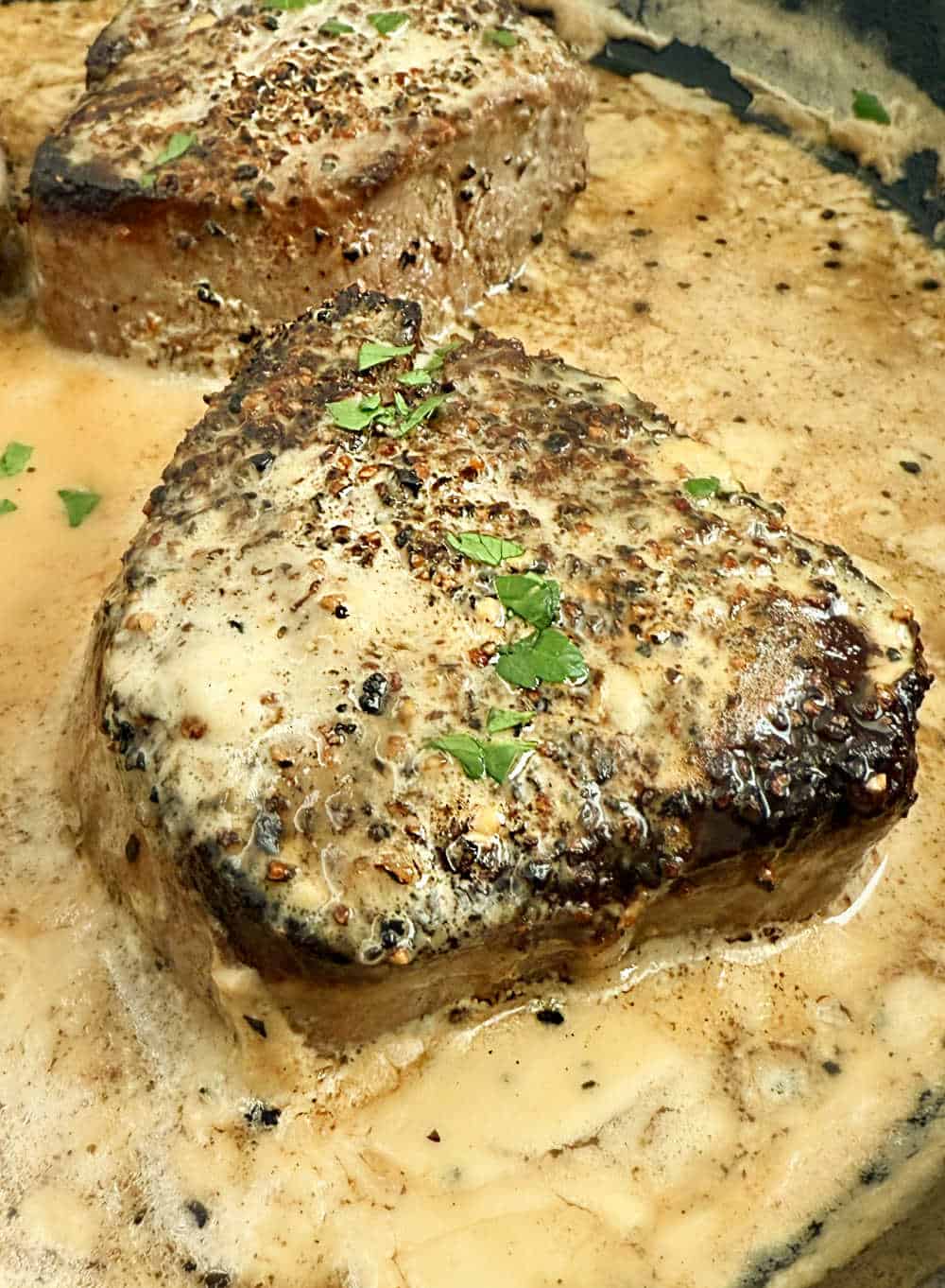 steak au poivre in skillet with creamy bourbon sauce.