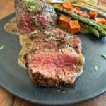 sliced steak au poivre in bourbon sauce on a plate.