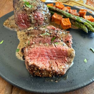 sliced steak au poivre in bourbon sauce on a plate.