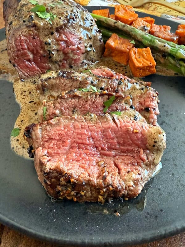 sliced steak au poivre in bourbon sauce on a plate.