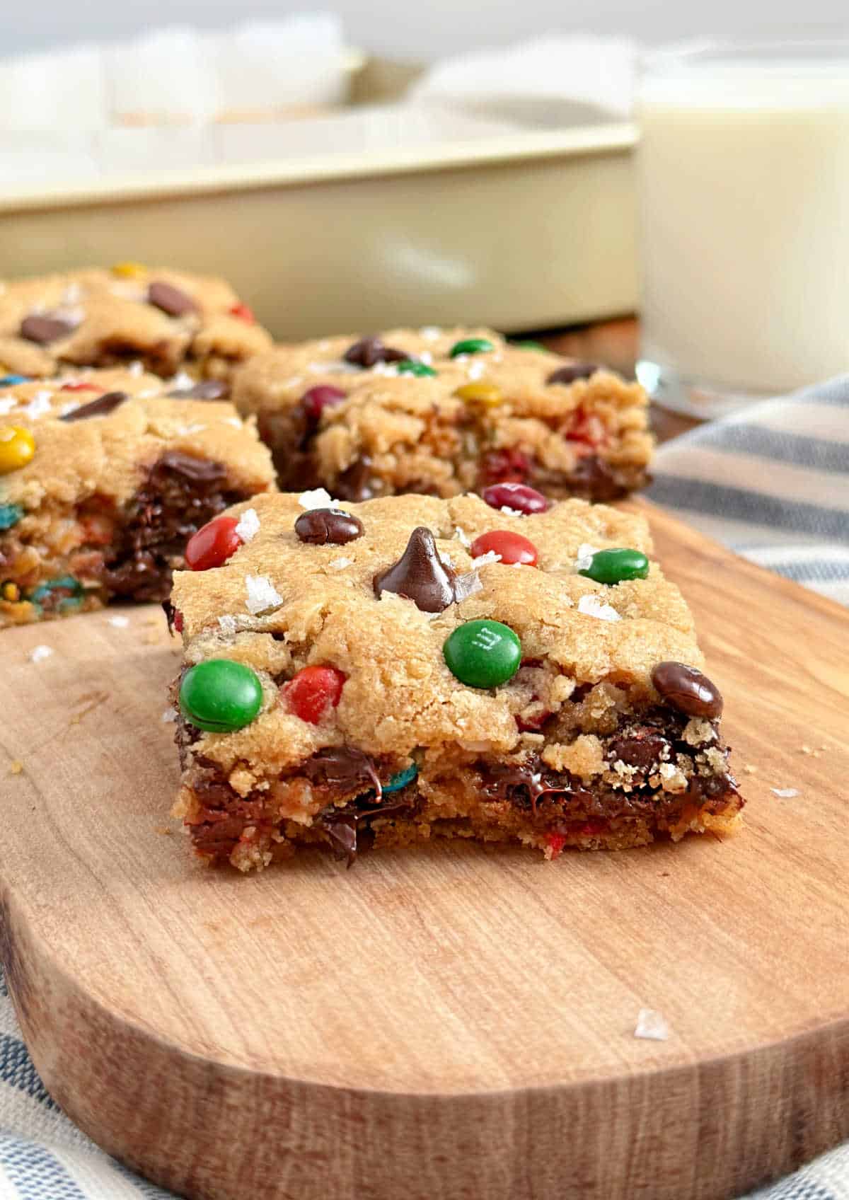 sliced monster cookie bars with m&m's and glass of milk.