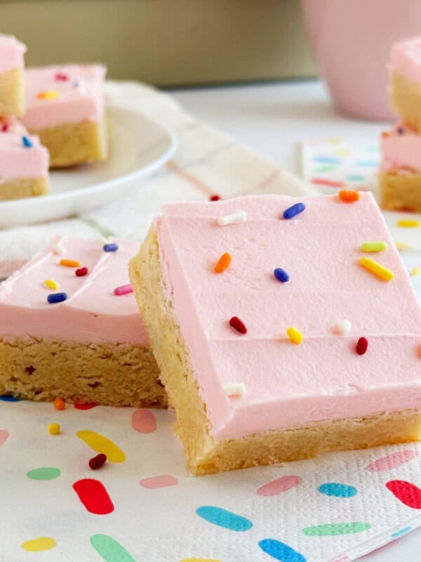 Sugar cookie bars with pink frosting and sprinkles.