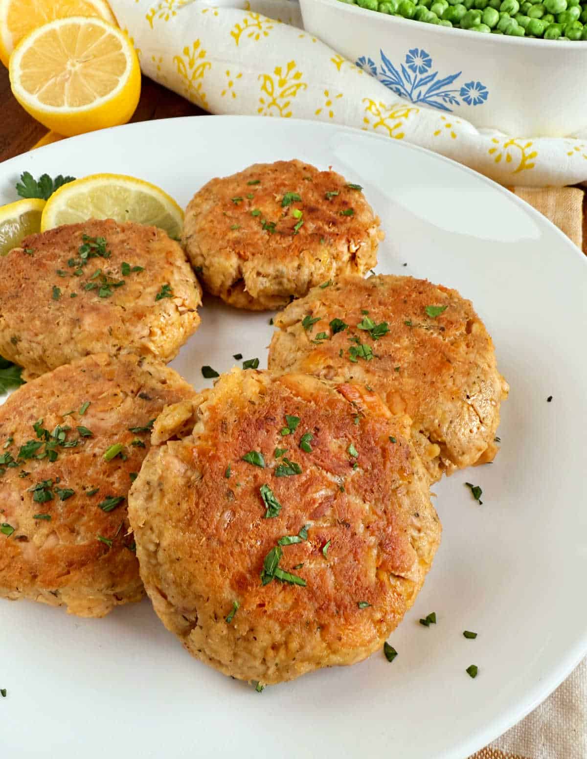 tuna patties with lemon and peas on the table.